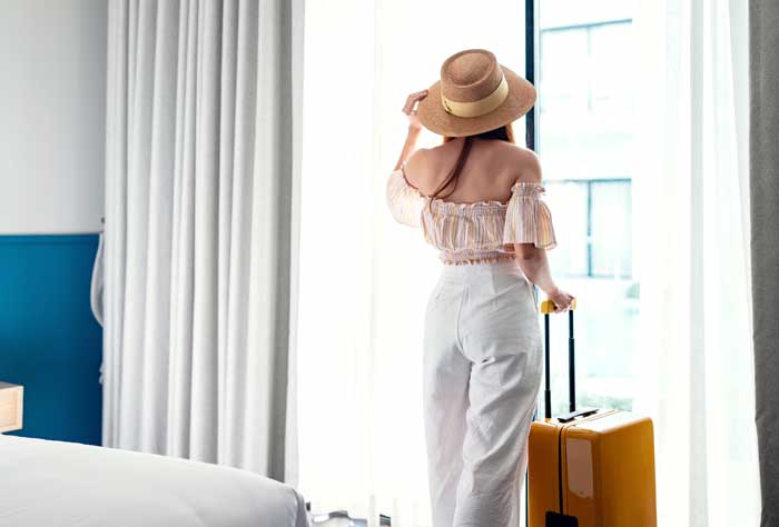 kobieta w słomkowym kapeluszu stojąca obok walizki