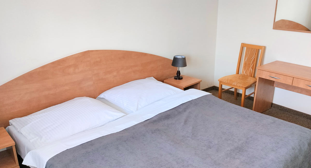 łóżko w sypialni apartamentu obok drewnianej komody