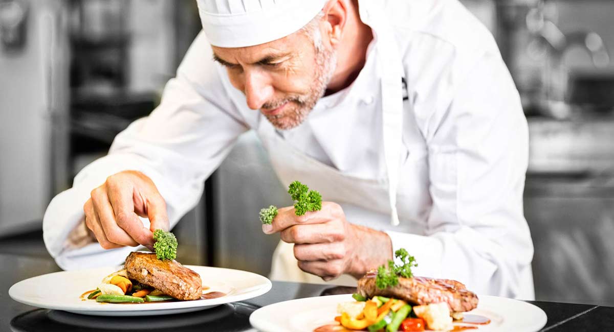 mężczyzna w czapce szefa kuchni nakłada brokuły na talerz