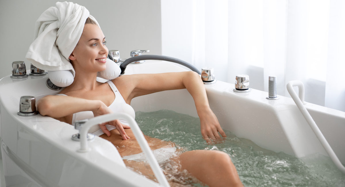 kobieta siedząca w wannie z ręcznikiem na głowie